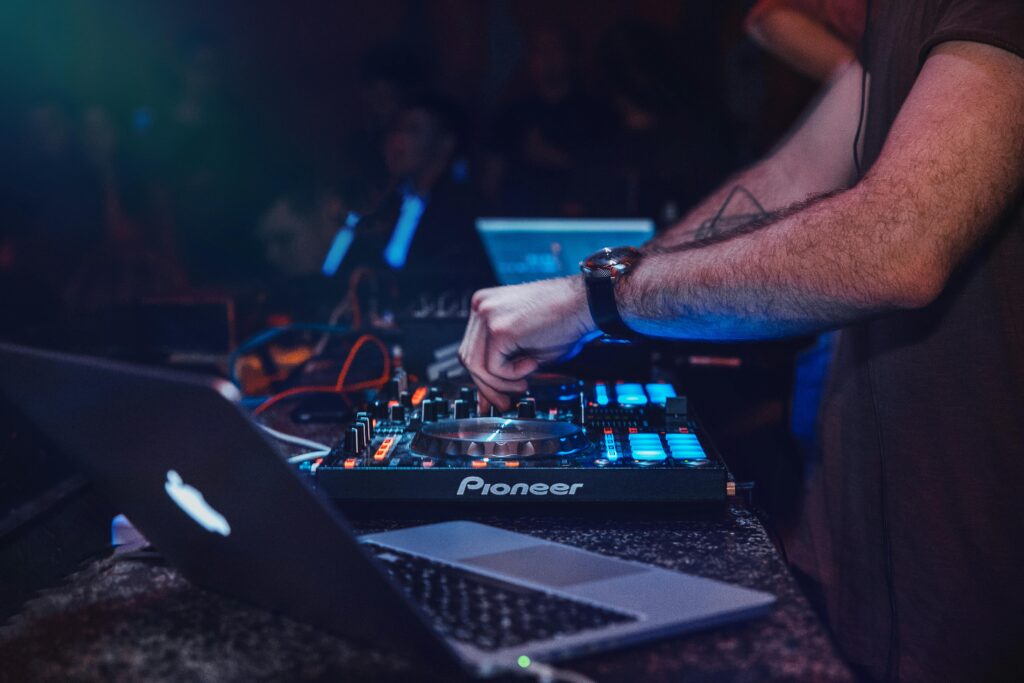 DJ justerer mixerpult under live performance med Pioneer-udstyr og laptop – DJ Gram tilbyder professionel og mobil DJ-service til private fester, firmaevents, fødselsdage og bryllupper i hele Danmark.