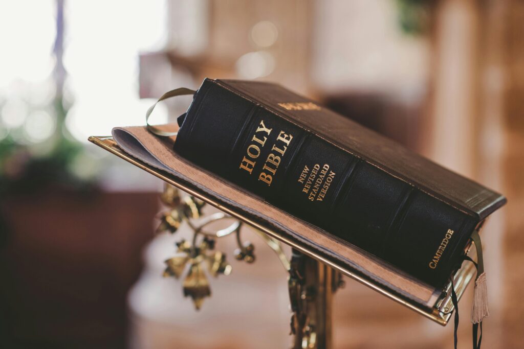 Nærbillede af Bibelen placeret på guldbelagt holder i kirkelig setting – DJ Gram tilbyder professionel DJ-service til konfirmationer, kirkefester og private religiøse events i hele Danmark.