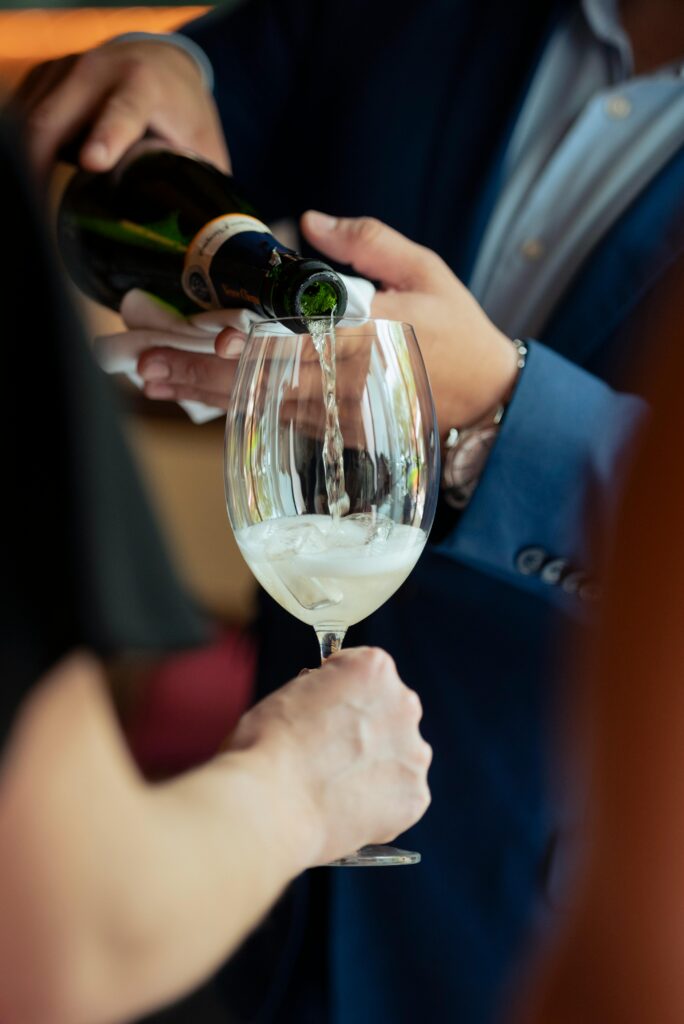 Nærbillede af en tjener, der skænker champagne i et glas med is til et elegant event – DJ Gram tilbyder DJ-service til private arrangementer, firmafester og eksklusive begivenheder i hele Danmark.