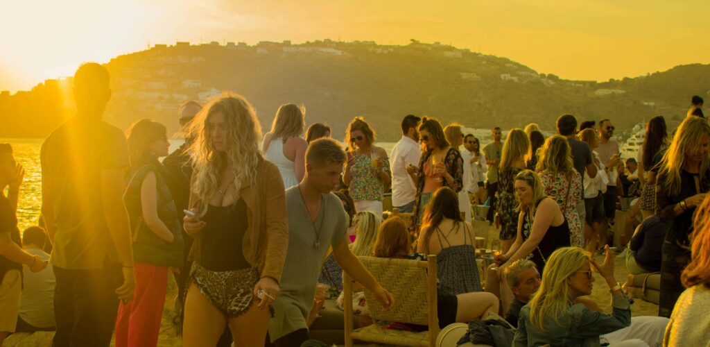 Stor udendørs strandfest ved solnedgang med mange unge mennesker, der danser og nyder musikken – DJ Gram tilbyder professionel DJ-service til private events og fester i hele Danmark.
