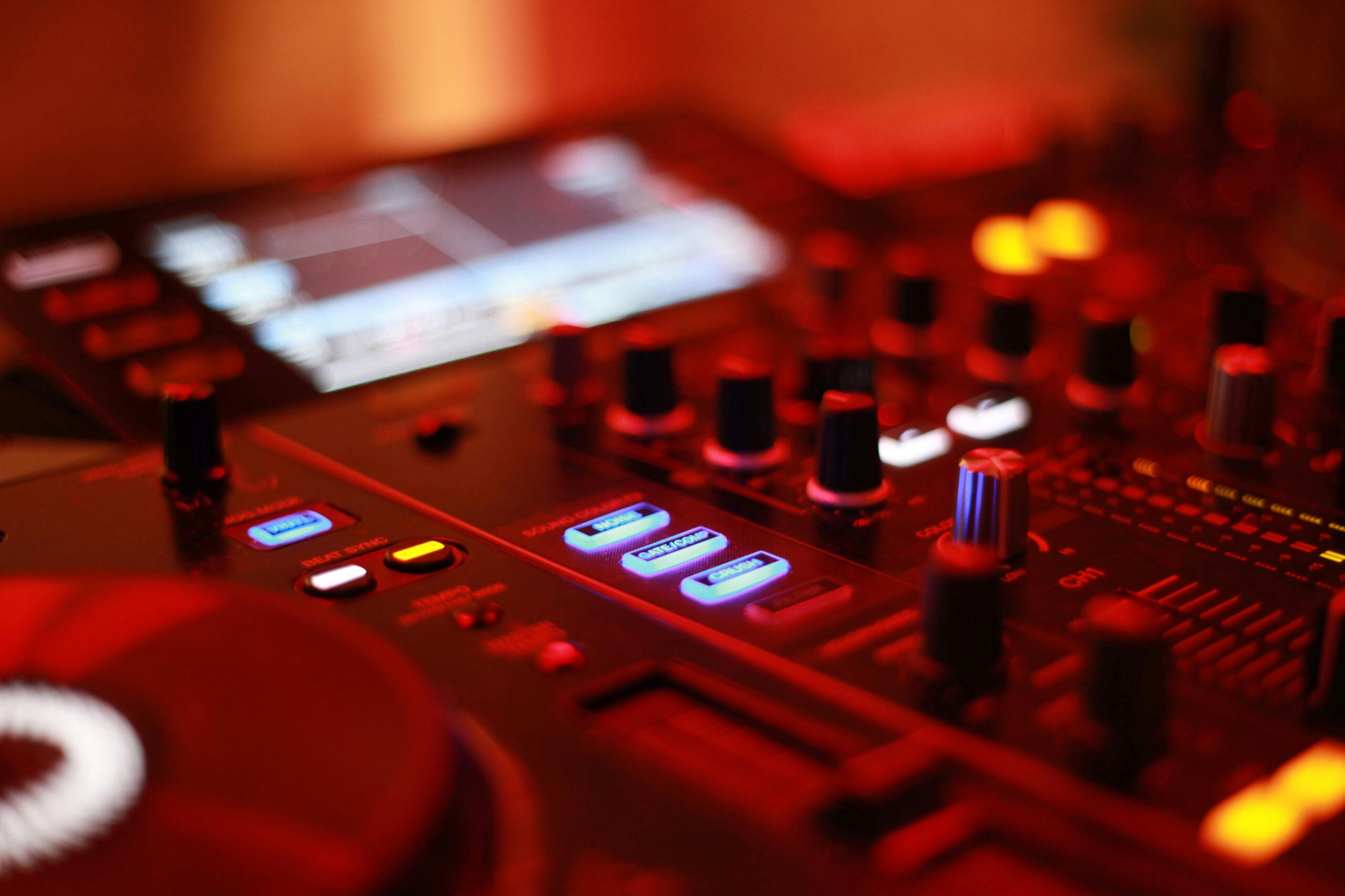 Nærbillede af professionelt DJ-mixerpult med lys og knapper i orange og blå nuancer – DJ Gram tilbyder mobil DJ-service med lyd- og lysudstyr til private fester, bryllupper, konfirmationer og firmaevents i hele Danmark.